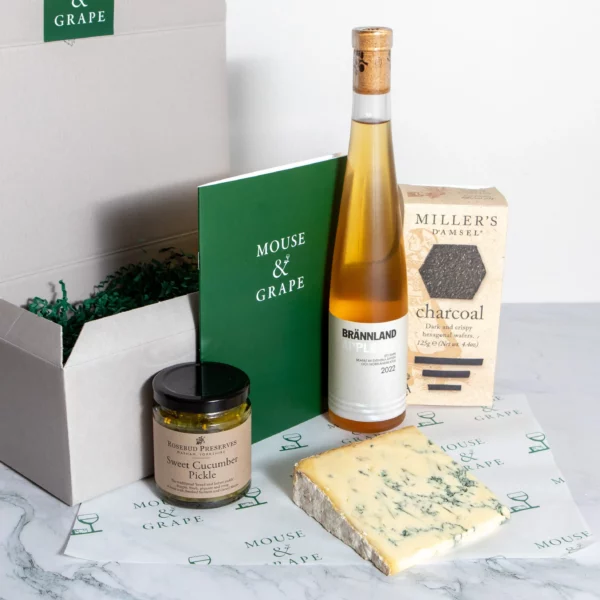 A hamper with one cider, sweet cucumber pickle, one cheese and crackers