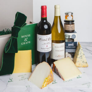 A hamper with two bottles of wine, four cheeses, crackers fruit cheese and honey