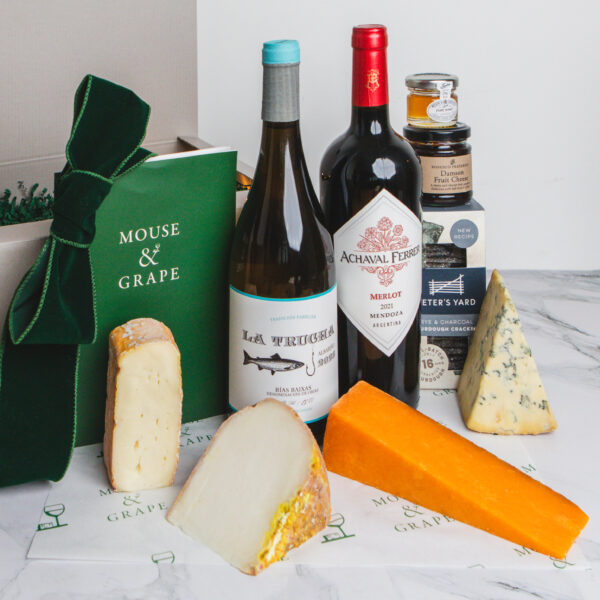 A Christmas hamper with two bottles of wine, four cheeses, cracker, fruit cheese and honey