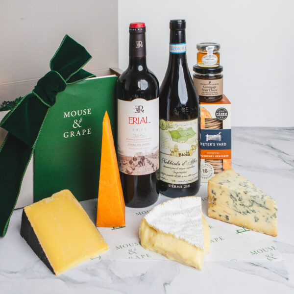 A christmas hamper with two red wines, four cheeses, a box of crackers, fruit cheese and honey