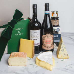 A red wine Christmas hamper with one bottle of port, one bottle of wine, four cheeses, a box of crackers, fruit cheese and honey